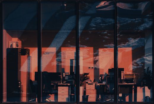 Moody office interior reflecting the evening cityscape through large windows.