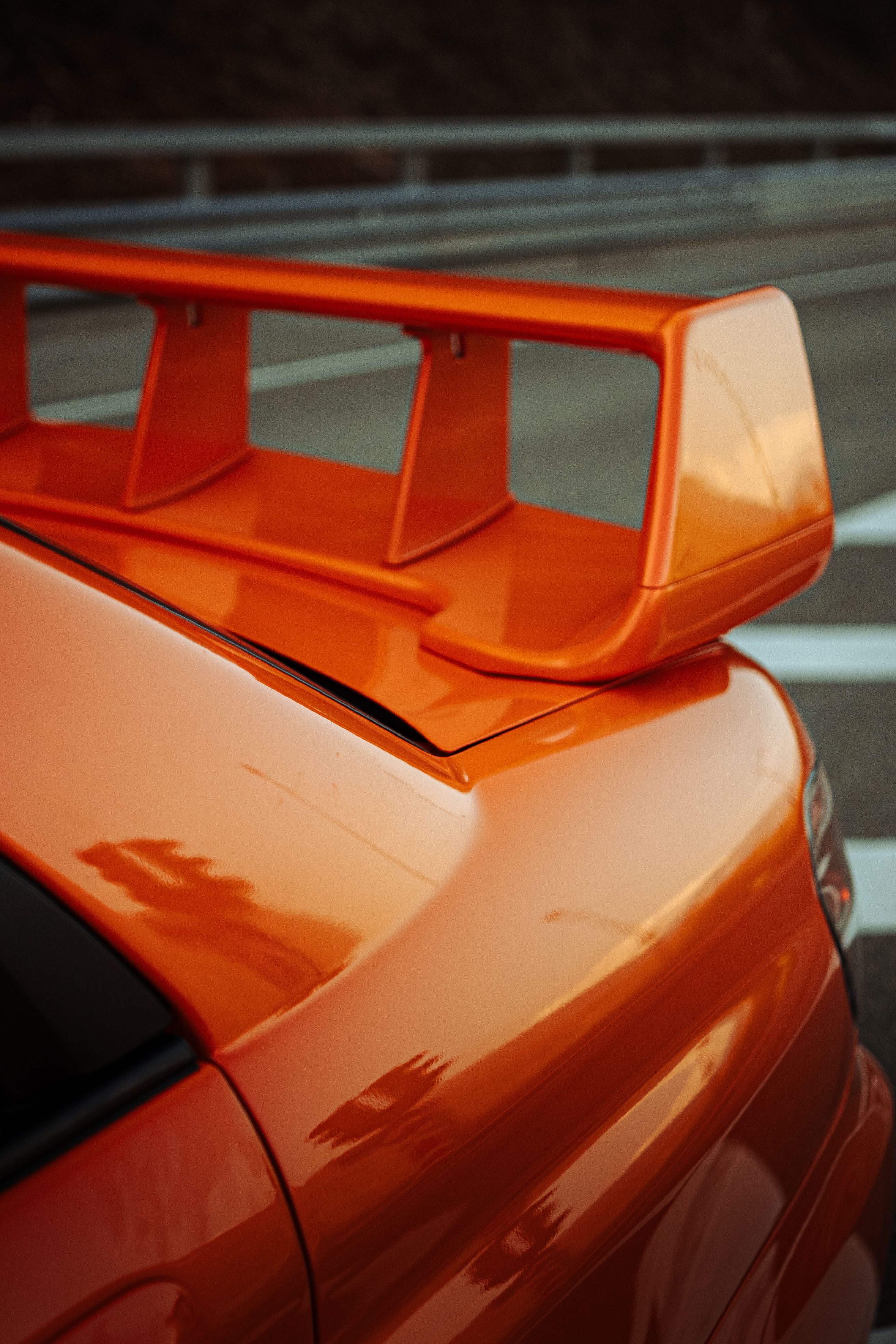 Detailed shot of an orange sports car spoiler, highlighting its sleek design.