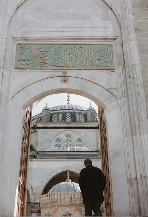 Free A man enters a mosque in Istanbul, showcasing Ottoman architecture with an ornate dome. Stock Photo