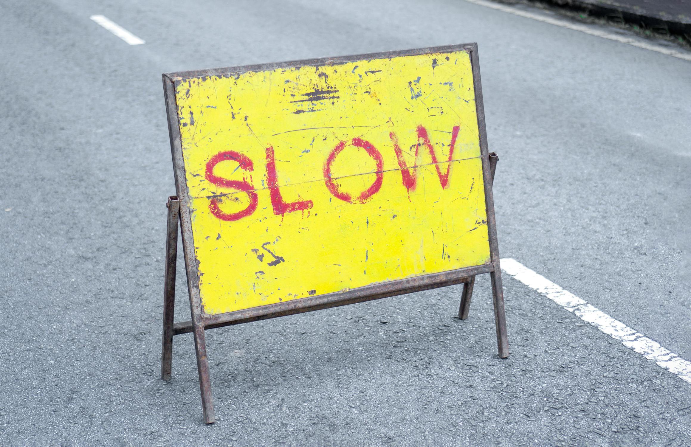 Yellow Slow Sign Standing in the Middle of an Asphalt Road · Free Stock ...