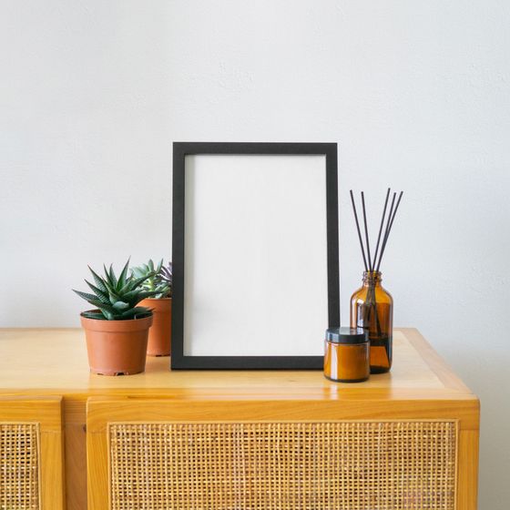 Empty black picture frame and succulents on a cane cabinet — photo by Komet Flicker on Pexels