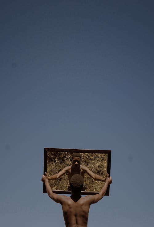 A man holding a mirror up to the sky