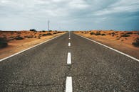 阿联酋迪拜，一条笔直空旷的沙漠道路延伸在多云的天空下，凸显出孤独与广阔