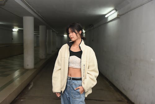 A woman in a white jacket and jeans standing in an underground parking garage