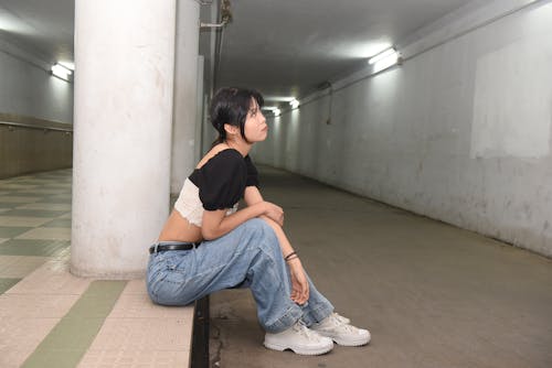A woman sitting on the ground in an empty hallway