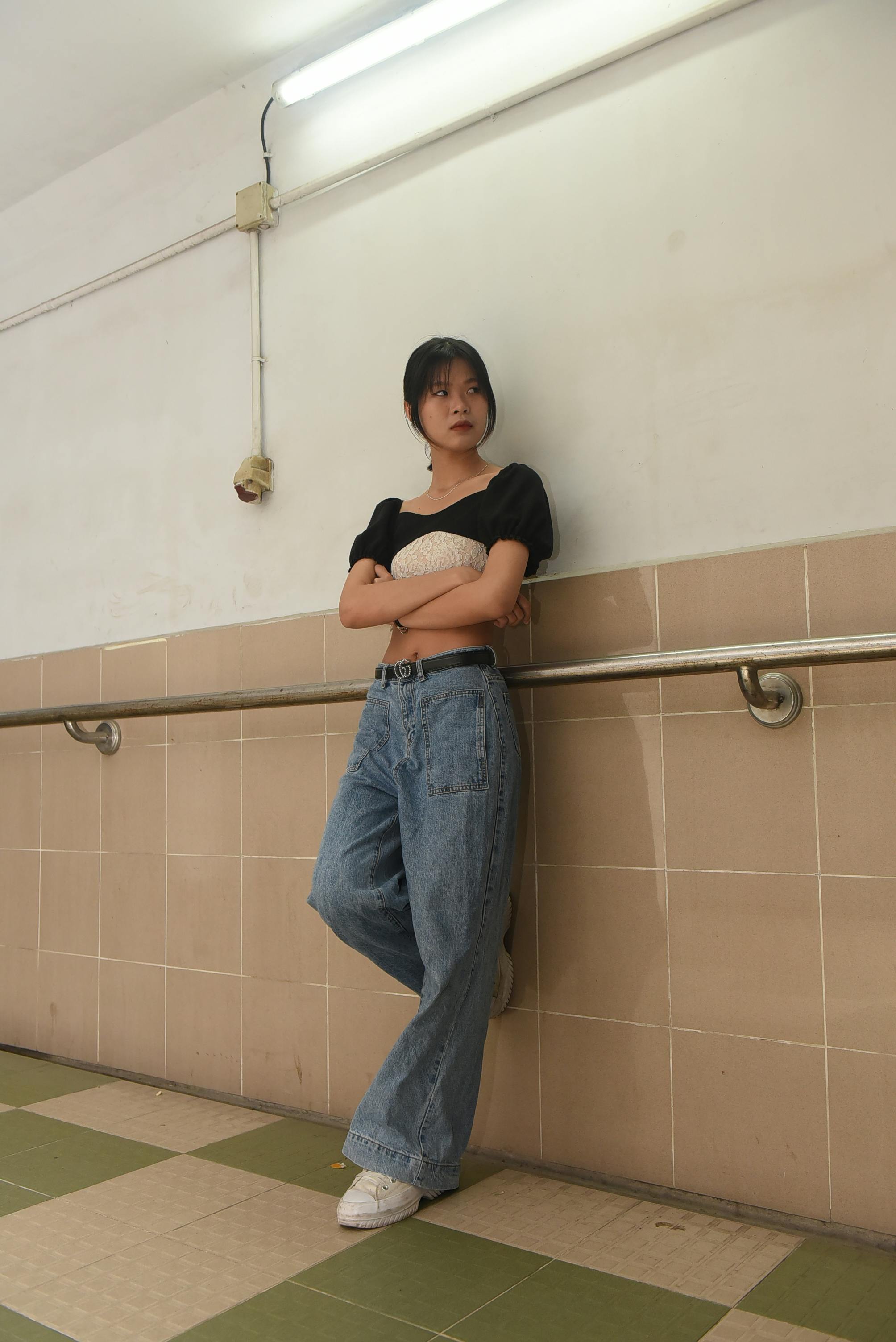 young woman in a casual outfit standing by the wall