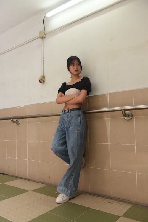 A young woman leaning against a wall in a bathroom