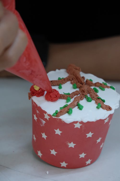 A person is decorating a cupcake with icing