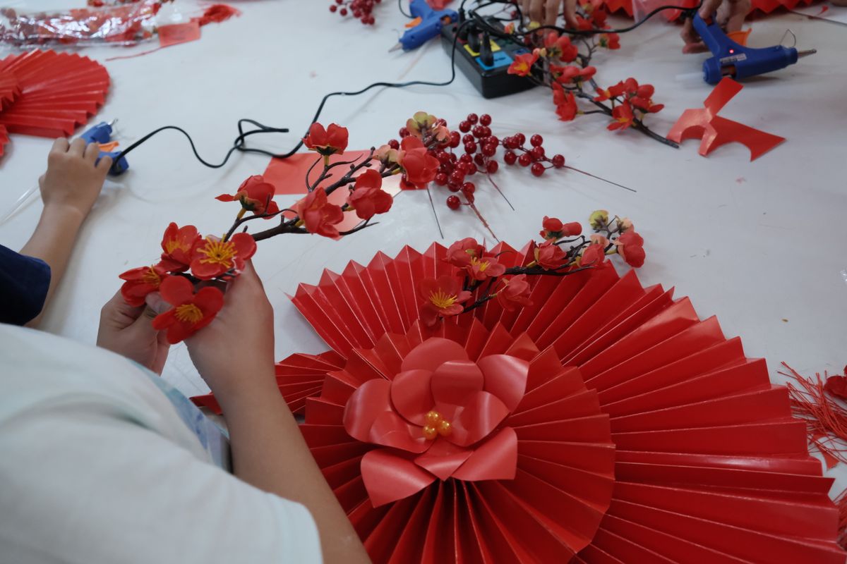 Hands crafting bold red paper flowers for a handmade bouquet