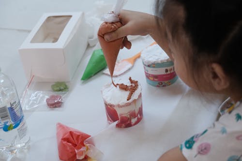A child is making a cake with icing