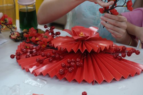Free Close-up of hands crafting a red paper fan with berry decoration. Stock Photo