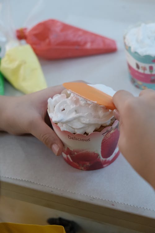 A child is making a cupcake with icing