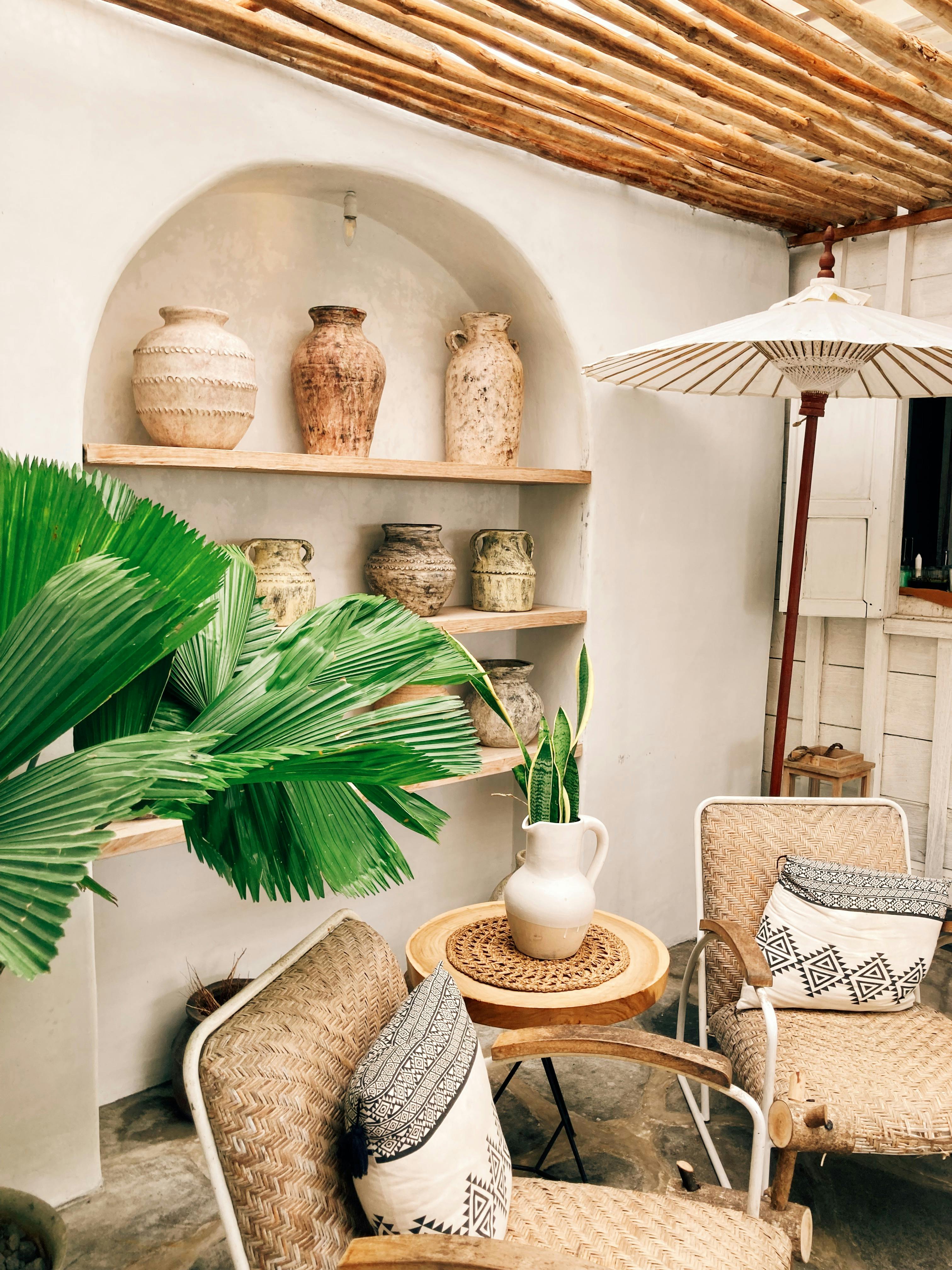 Cozy outdoor seating with boho decor, vases, and tropical plants in a serene setting.