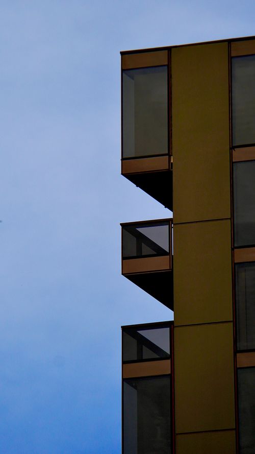 Free Minimalist view of a modern apartment building in Adelaide, showcasing glass balconies against a clear sky. Stock Photo