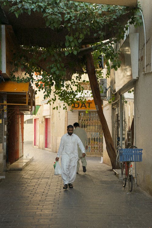 A man walking down a narrow alleyway with a basket