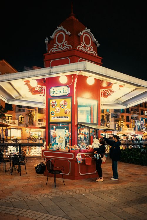 Free An illuminated city street kiosk with people at night, creating a vibrant urban scene. Stock Photo