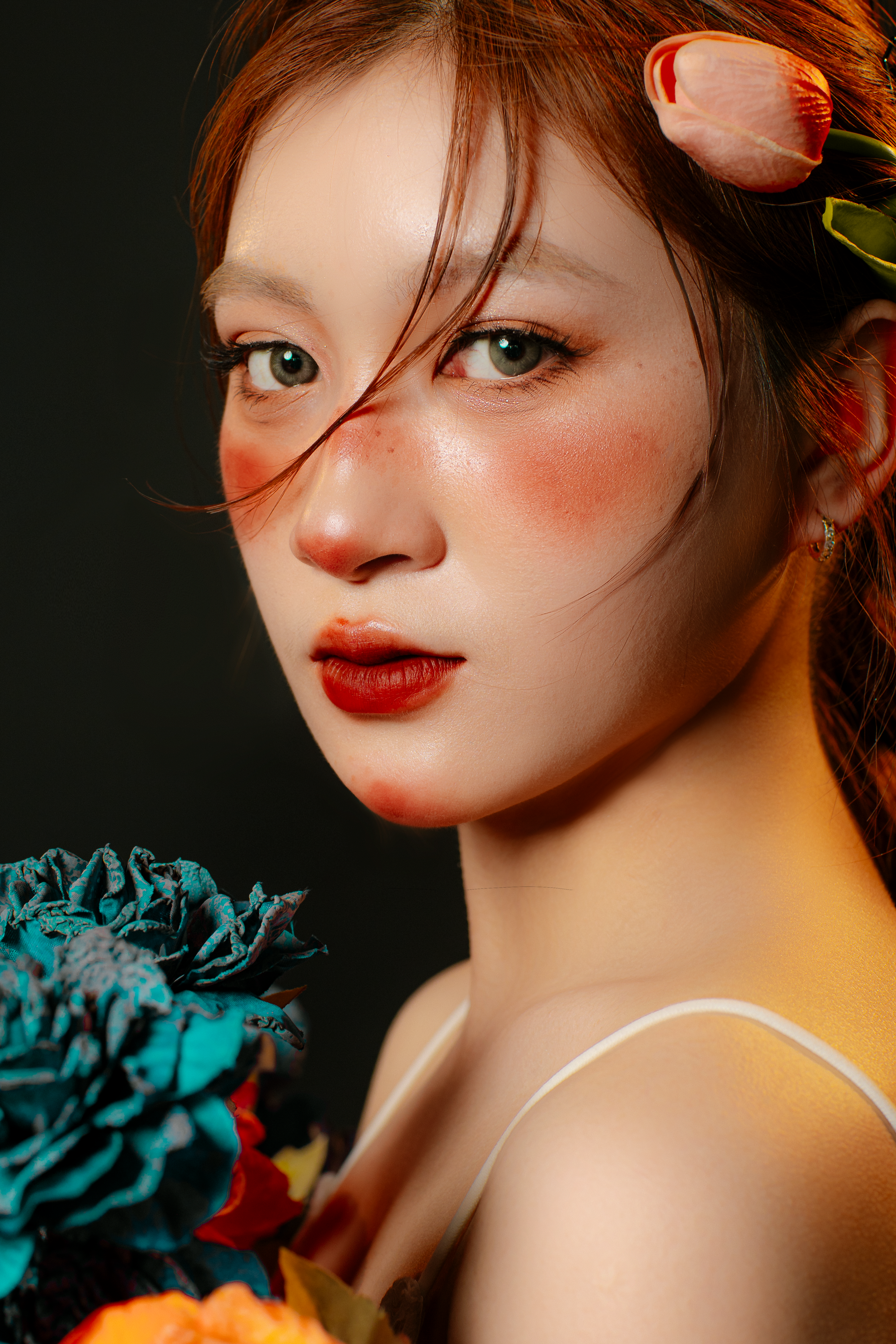 Striking portrait of a woman with vivid makeup and colorful flowers, exuding elegance and beauty.