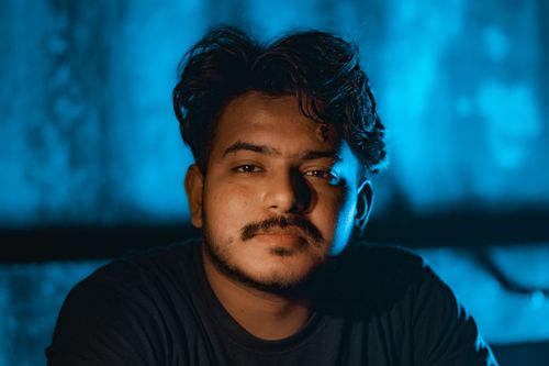 Free Close-up portrait of a young man with a thoughtful expression against a blue backdrop. Stock Photo