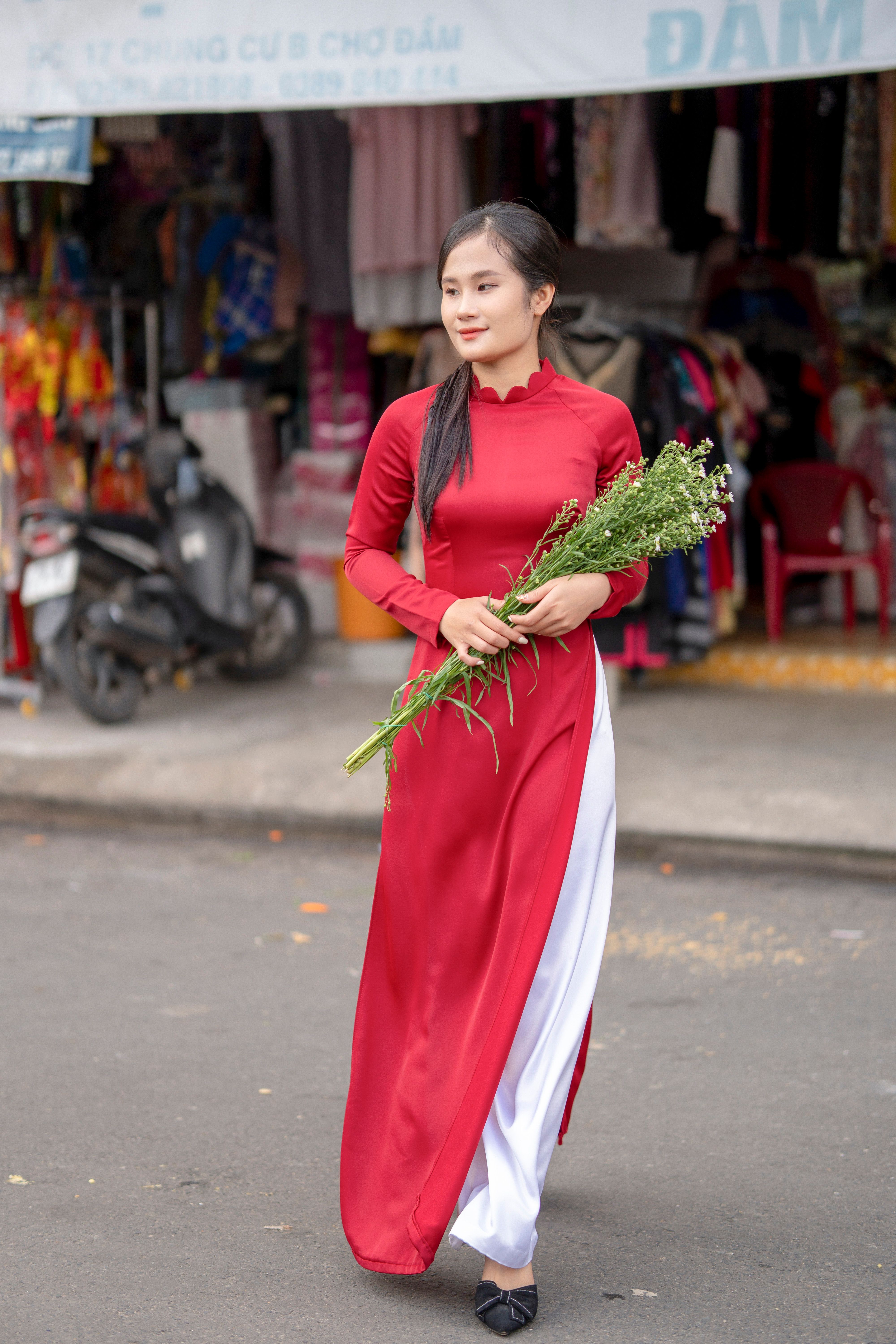 Elegant Woman in Red Dress Holding Flowers Outdoors · Free Stock Photo