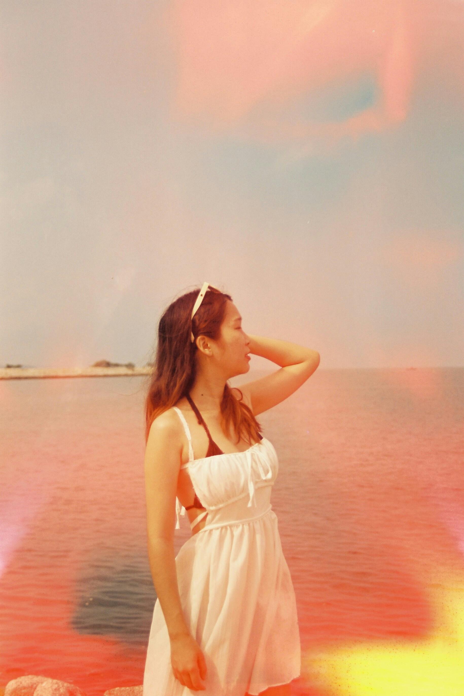 A woman in a white dress enjoying a peaceful day by the sea in Pattaya, Thailand.
