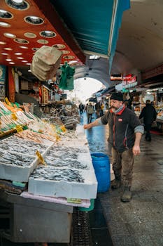 Vibrant indoor fish market scene with fresh seafood and an attendant arranging the display.