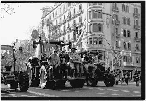 A black and white photo of tractors on the street