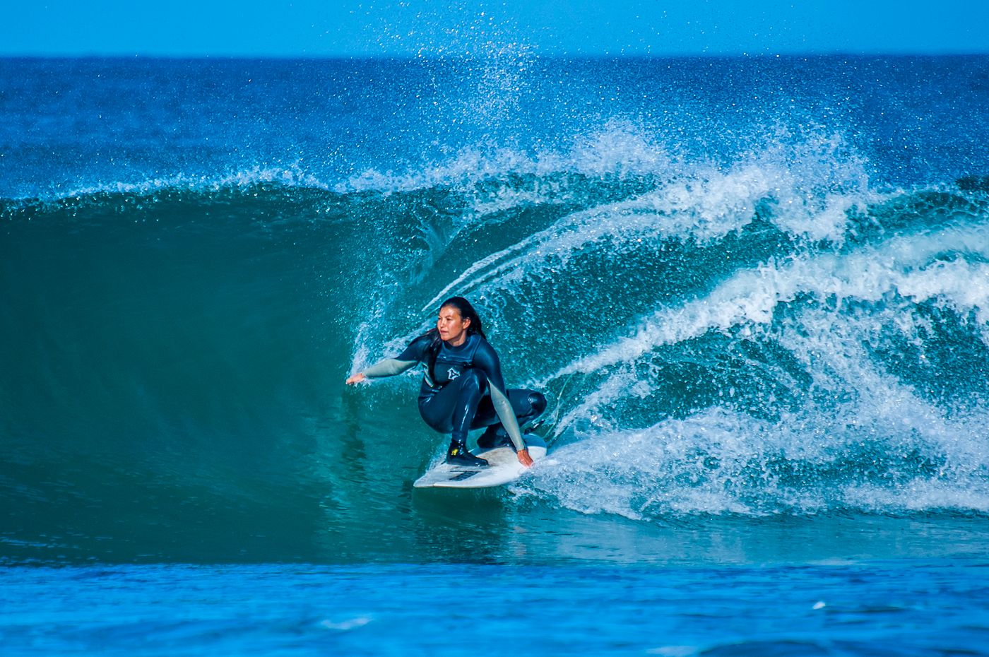 A woman skillfully surfs a large wave at Jeffreys Bay, South Africa.