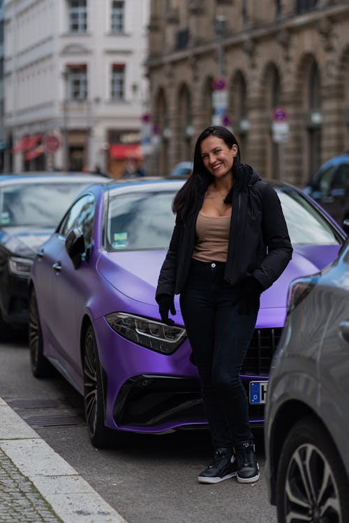 A woman standing next to a purple car