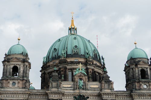 A large building with a dome and two green domes
