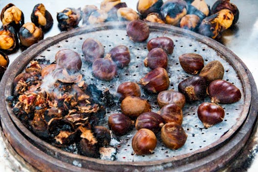 Close-up view of roasted chestnuts smoking on a round grill, emphasizing texture and warmth.