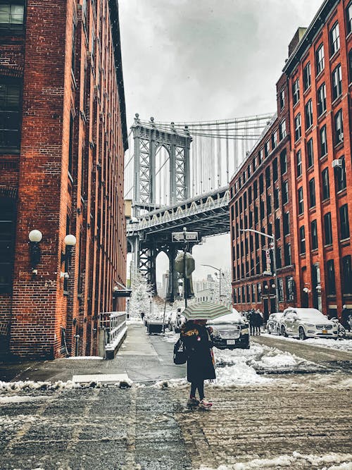 A person walking down a snowy street with an umbrella