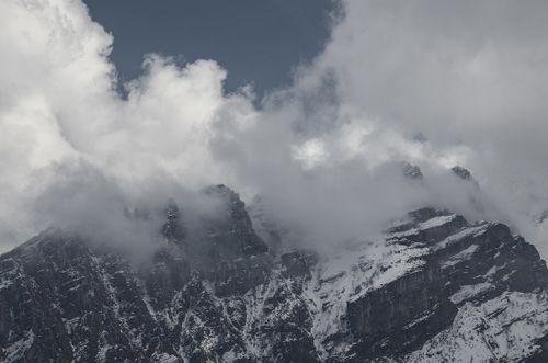 Free Snow-covered mountain peaks partially shrouded by clouds, showcasing nature's dramatic beauty. Stock Photo