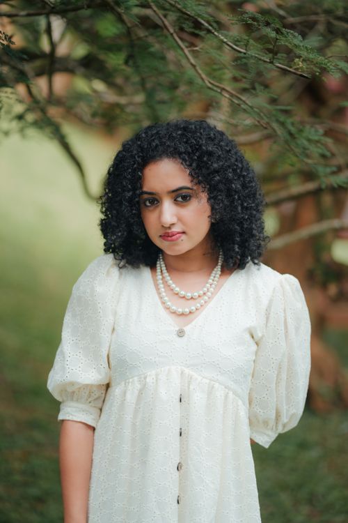 Free Portrait of a woman in a white dress amidst lush greenery in Thodupuzha, India. Stock Photo