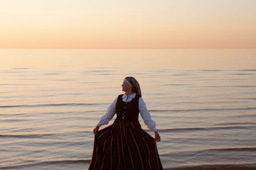 Nun Standing in Ocean at Dusk