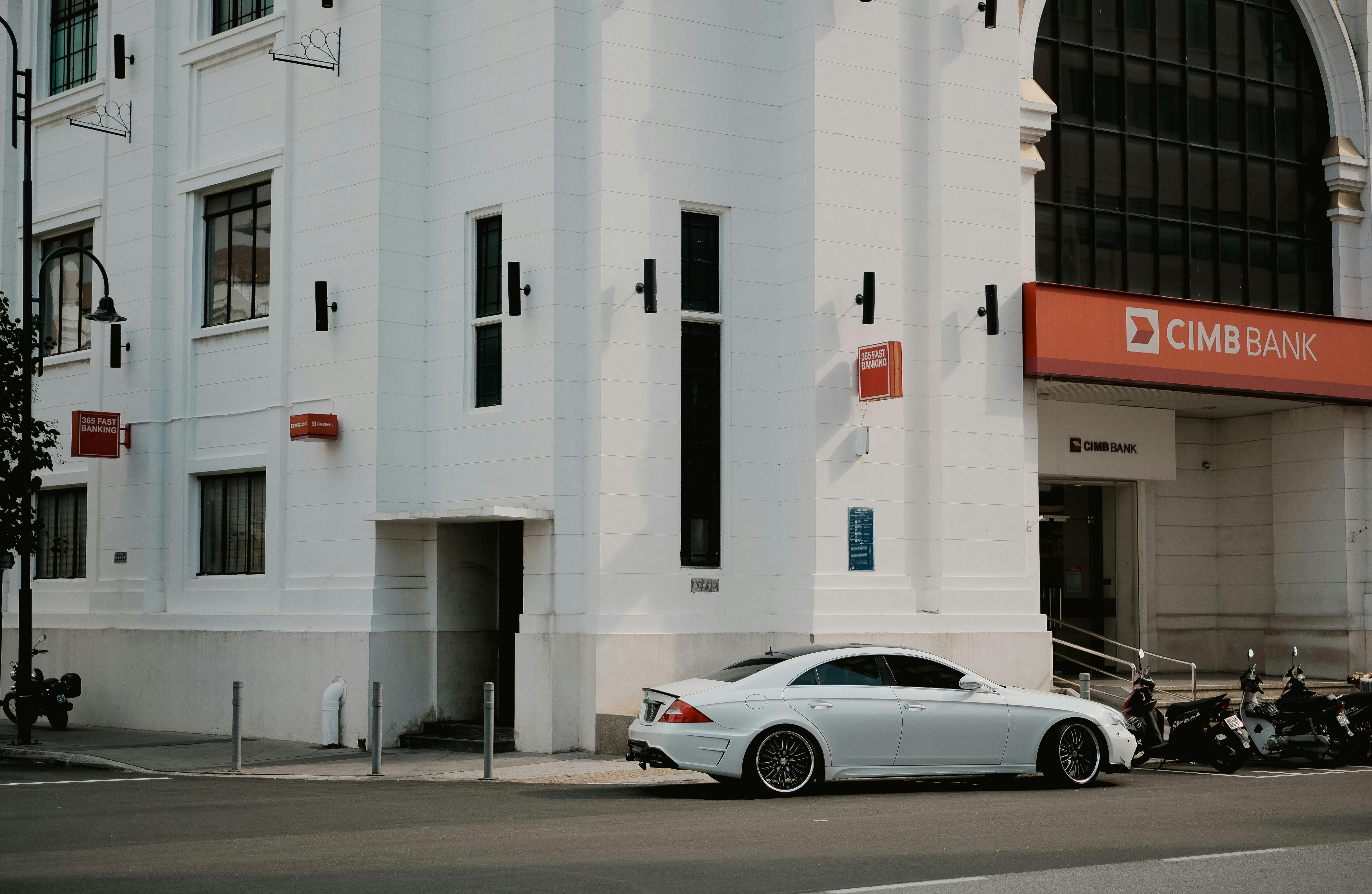 White Modern Car Parked in front of Large White Bank Building