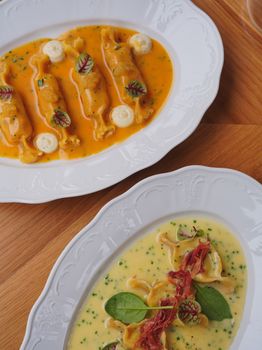 Top view of gourmet ravioli dishes in flavorful sauces, plated elegantly.