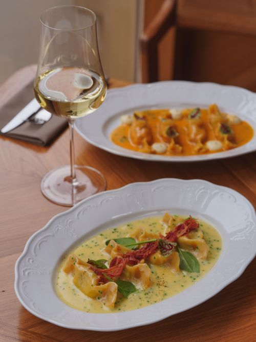 Free Delightful gourmet pasta dishes paired with fine white wine on a wooden table. Stock Photo