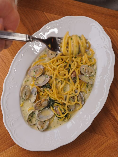Free Freshly cooked spaghetti with clams in a creamy sauce, captured in a top view on a wooden table. Stock Photo