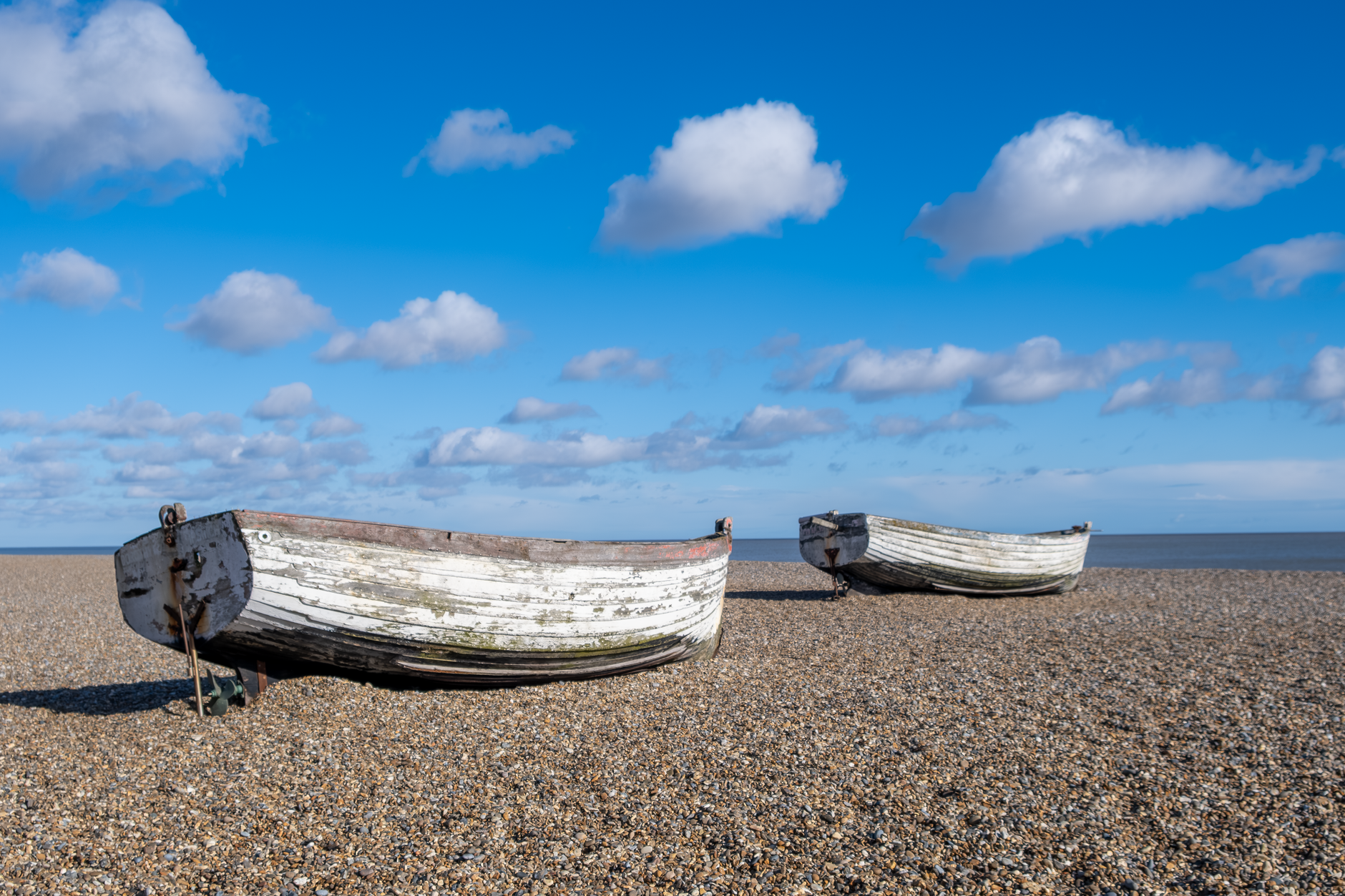 Traditional wooden fishing boats resting on the pebbled shingle beach at Aldeburgh, Suffolk