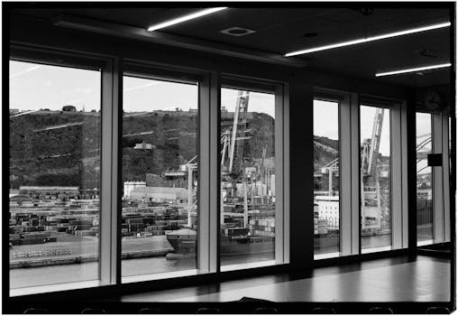 Black and white view of Barcelona's industrial harbor through large windows.
