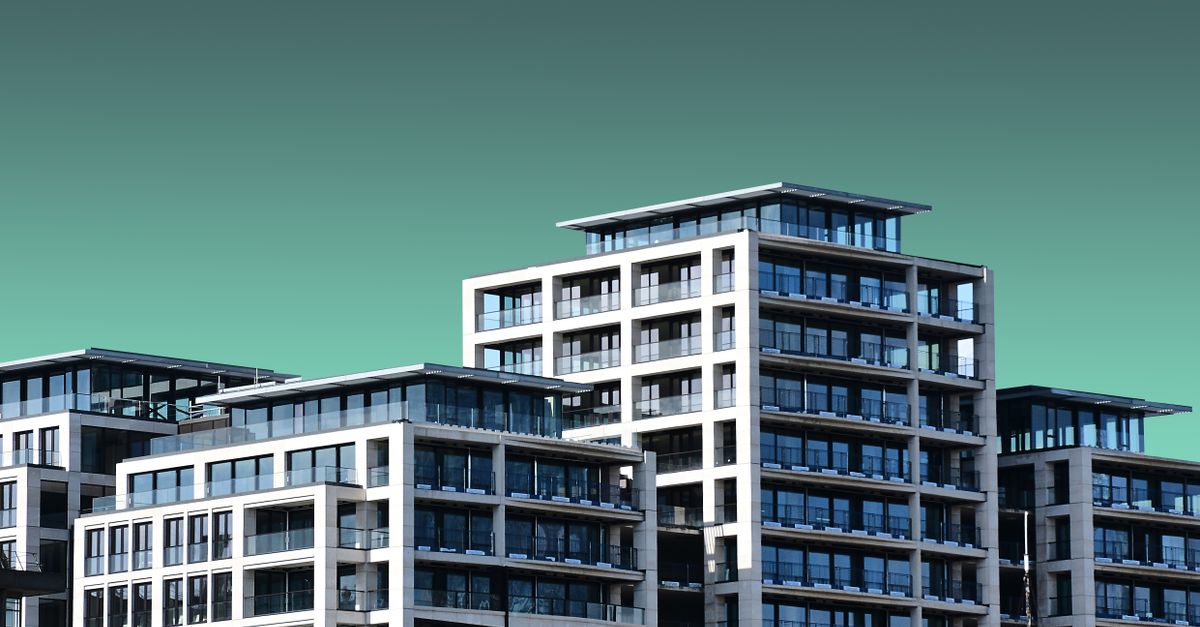Contemporary apartment buildings with a minimalist design are set against a clear blue sky.