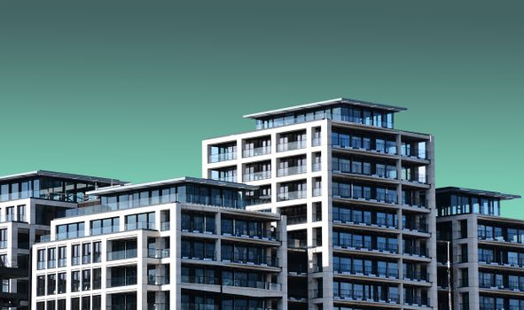 Contemporary apartment buildings with a minimalist design are set against a clear blue sky.