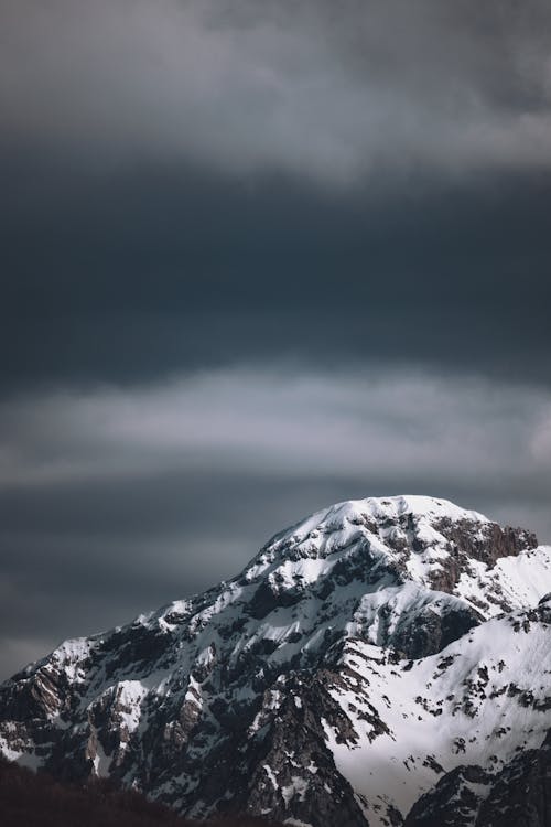A snow covered mountain with dark clouds in the background