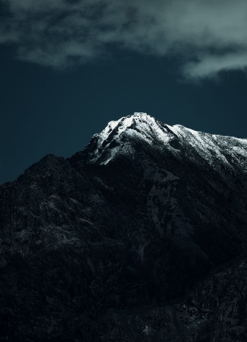 Free A breathtaking view of a snowcapped mountain peak under a night sky with clouds. Stock Photo