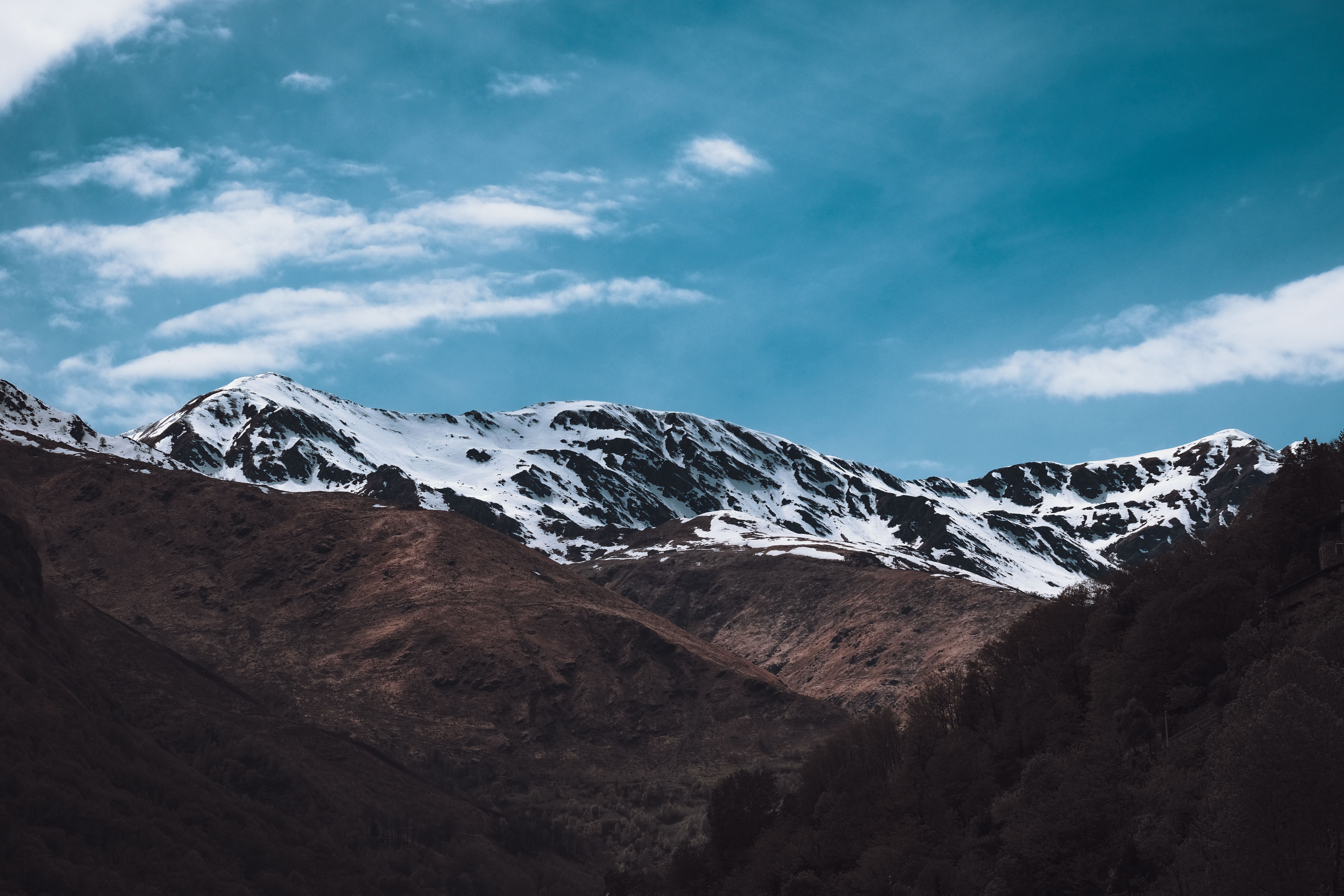 A mountain range with snow capped peaks and blue sky · Free Stock Photo