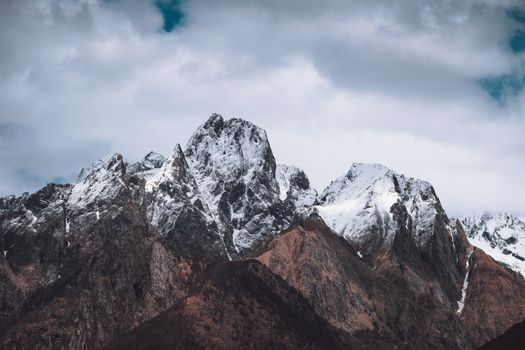 Explore breathtaking snow-covered mountain peaks against a cloudy sky in this stunning landscape photograph.