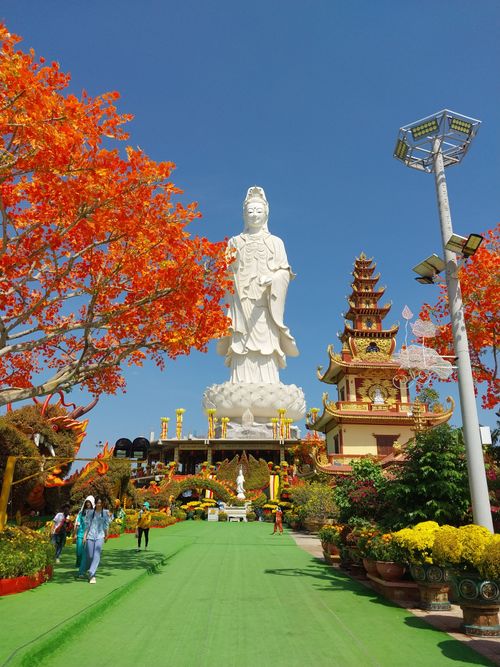 Free A vibrant temple featuring an impressive Guan Yin statue surrounded by autumn foliage. Stock Photo