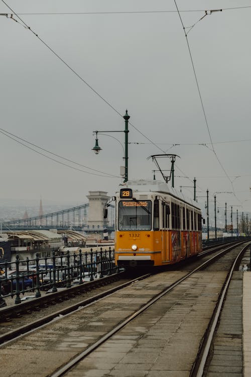 A yellow train on tracks next to a bridge