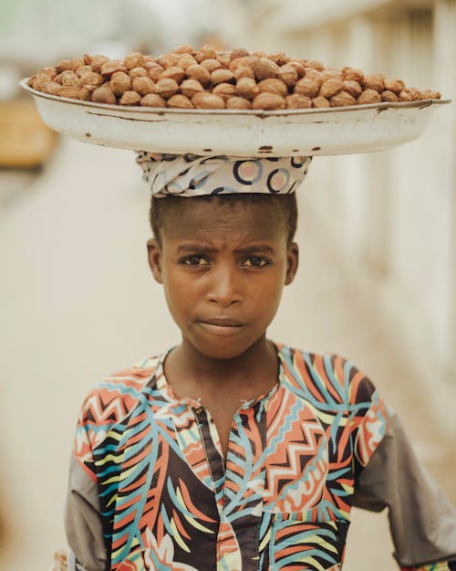 A young girl carrying nuts on her head