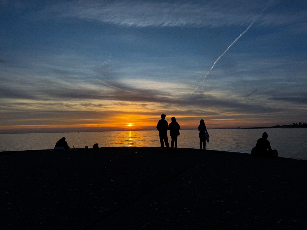 silhouettes of people enjoying the beautiful sea view during sunset cr